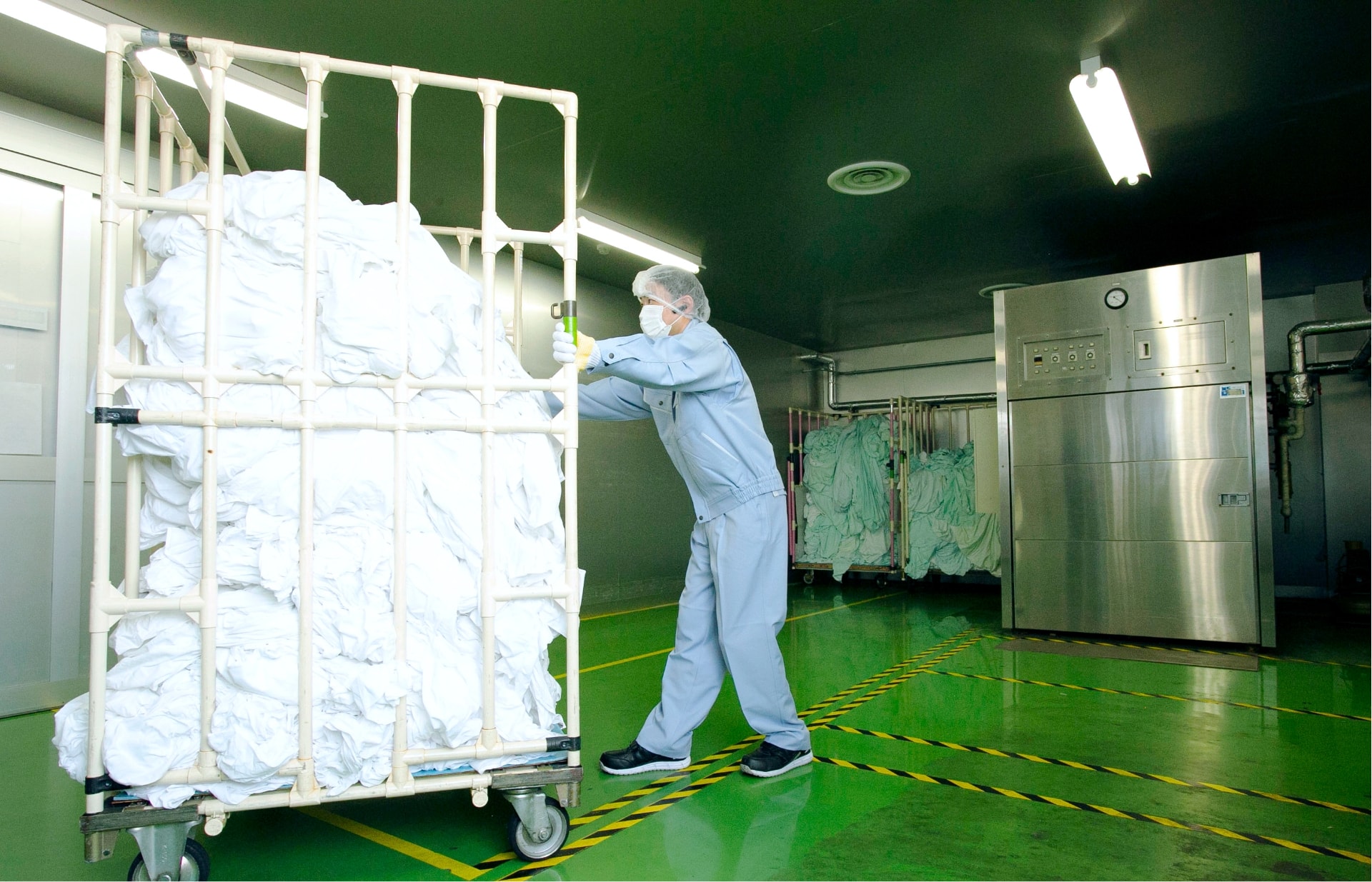 男性作業員が感染の恐れのあるリネン品を消毒室に集めている写真